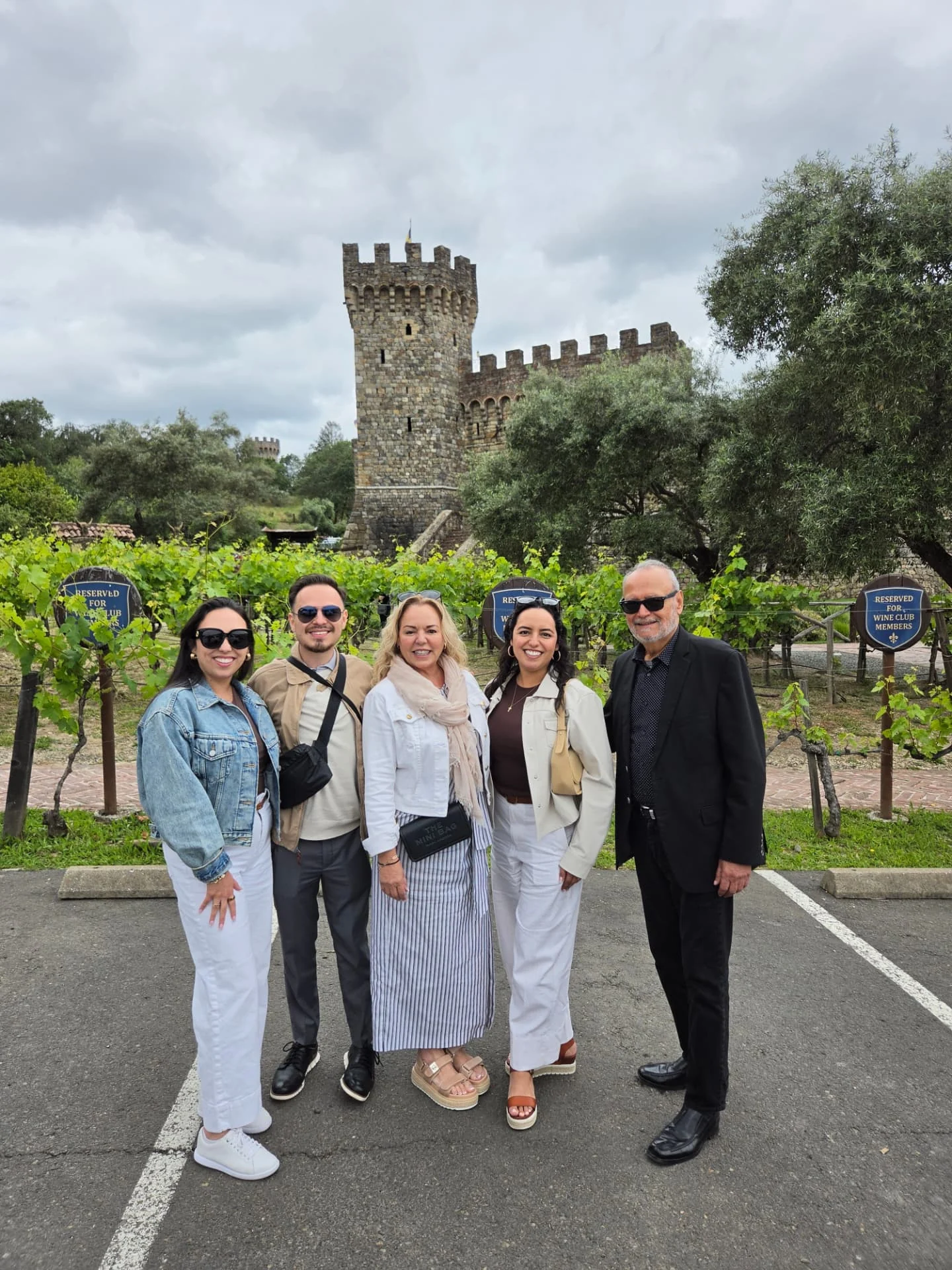 Five guests at a vineyard near a castle-style winery.