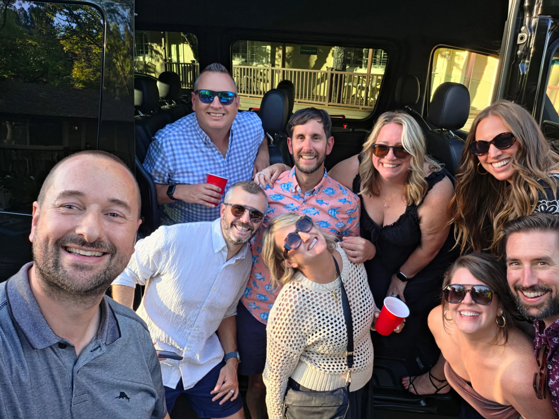 Guests smiling together at the open passenger-van door.