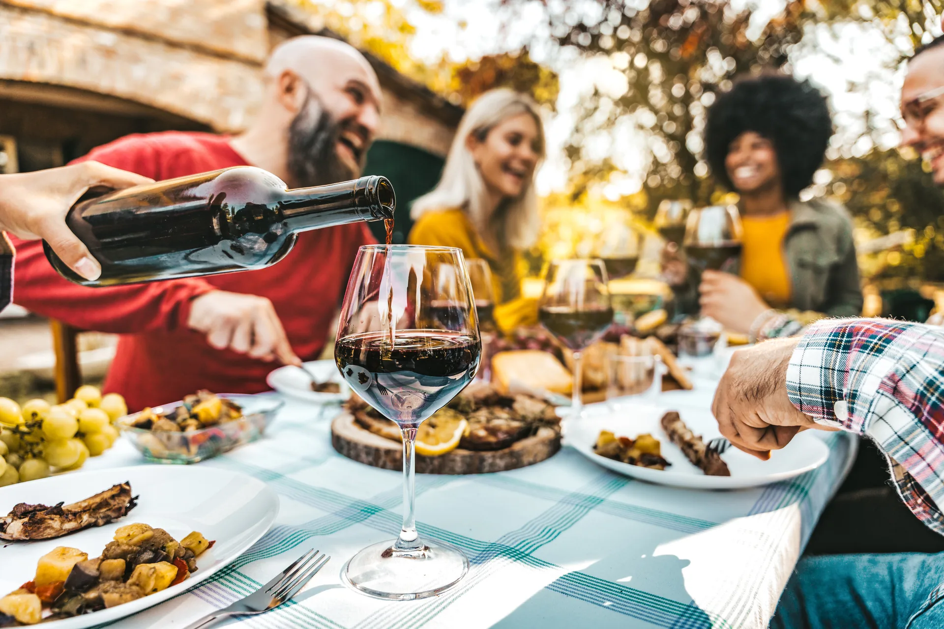 Outdoor wine tasting experience in Napa Valley with guests enjoying premium wines in scenic vineyard setting with beautiful natural landscape