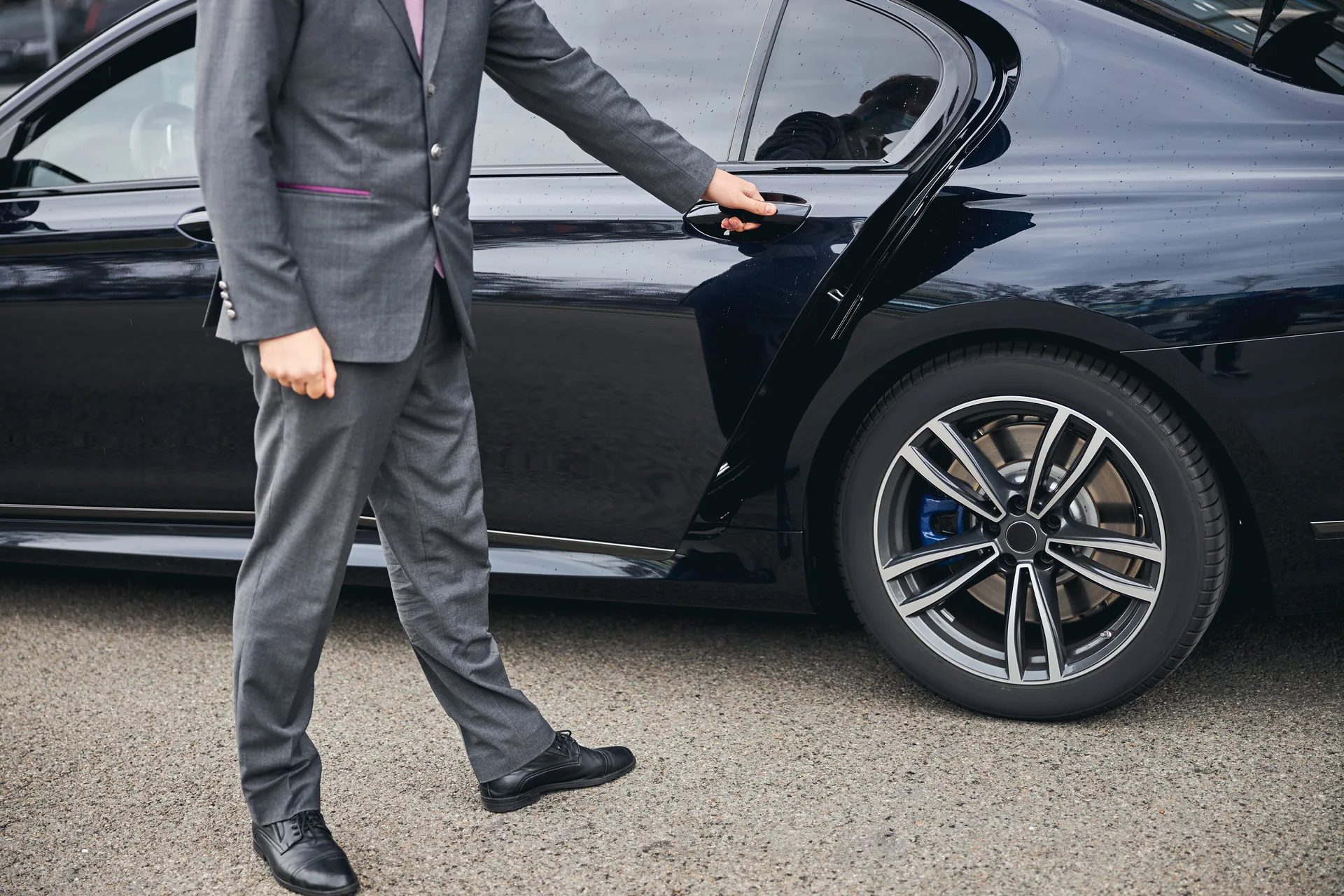Professional chauffeur opening luxury vehicle door providing premium white-glove service for Napa Valley wine tour transportation